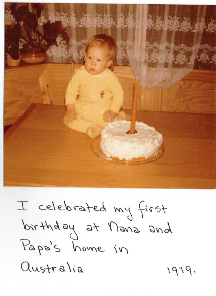 the author when he was a baby.  the author is sitting on a table to celebrate his first trip around the sun.  a food item is on the table. 
